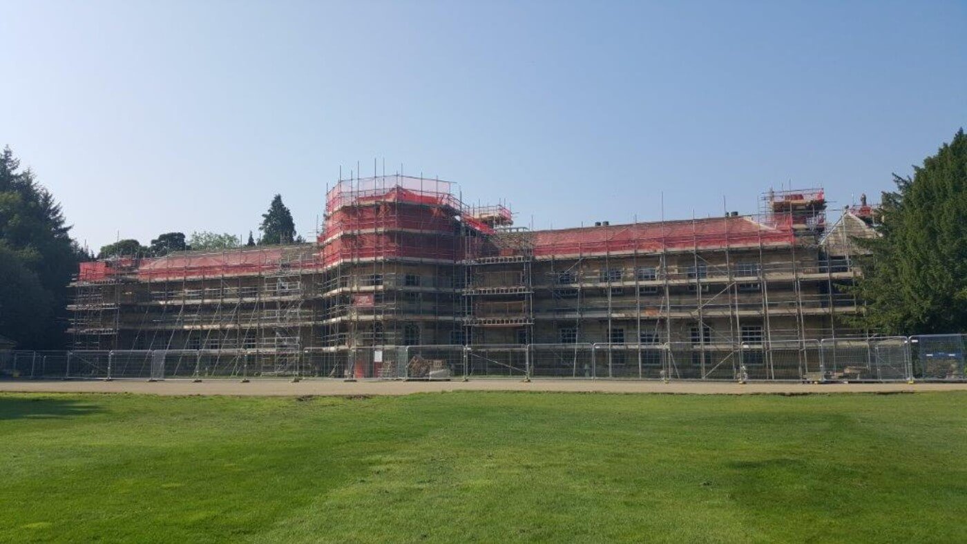 scaffold covers a large historical building in rural setting
