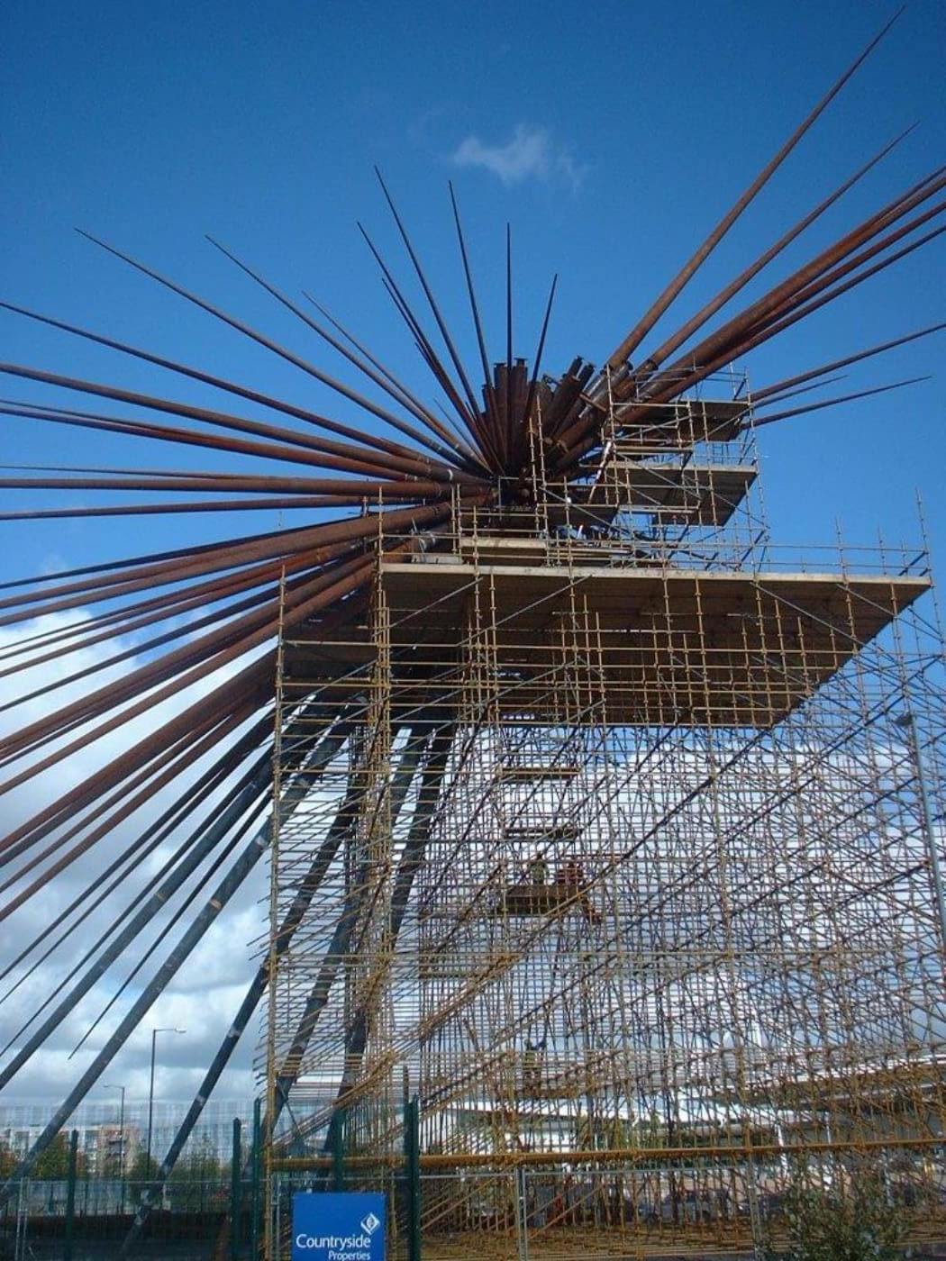 a scaffold tower supports construction materials against a blue sky